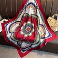 Détail d'un foulard en satin rouge aux motifs de chaînes vintage sur un canapé en cuir - 90x90cm / Rouge