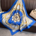 Vue détaillée des motifs de chaînes luxueux et de la texture en soie bleue du foulard carré - 90x90cm / Bleu