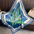 Détail du motif floral de muguet sur un foulard drapé sur un canapé en cuir - Bleu