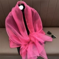 Détail d'une écharpe en soie rose vif translucide et légère sur une surface texturée sombre - Rouge Rose