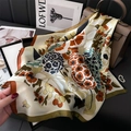 Elegant floral print silk scarf in orange and olive green draped on a luxury handbag - Army Green