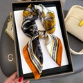 Detail of floral chain print silk scarf tied in a bow on a luxury display tray - Orange Black (FJ816-3)