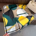 Détail d'un foulard en soie à motifs géométriques sur un canapé avec des accessoires - Patchwork Géométrique Jaune et Vert (FJ828-2)