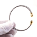 Detailansicht der gedrehten Silberkabel-Manschette mit polierten goldenen Kugelenden - Gold und Silber Zweifarbig