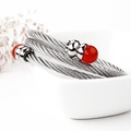 Zilveren gedraaide kabelarmband met rode kralen op minimalistisch wit keramiek - Rode steen