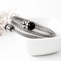 Detail van zilveren gedraaide kabelarmband met zwarte kralen op een witte achtergrond - Zwarte Steen