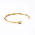 Macro detail of the twisted rope design on an 18k gold-plated stainless steel cuff bracelet - Gold