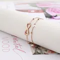 Detail of rose gold double-layered infinity anklet with pearls on a decorative scroll - Rose Gold