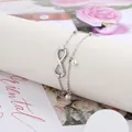 Detail of silver infinity charm and white pearl pendants on a double-layer chain - Steel