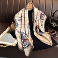 Macro view of camellia silk scarf showing detailed rose patterns and pearl chain motifs - Camel