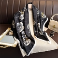 Detailed view of camellia flower print on silk scarf draped over white knitwear - Black with White Trim