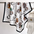 Detailed view of silk camellia scarf with black border and floral pattern on a hanger - White