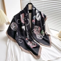 Detailed close-up of a 90cm camellia silk scarf with floral patterns on a white hanger - Coffee Edge
