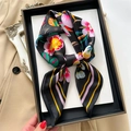 Dettaglio di un foulard di seta floreale annodato a fiocco su vassoio nero - Nero