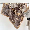 Detail of printed silk scarf with floral and celestial patterns hanging on a metal rod - Champagne (FN189-3)