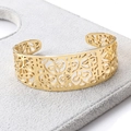 Detailed close-up of gold stainless steel open bangle with hollow floral patterns - Gold
