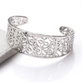 Detailed macro view of an open stainless steel cuff bracelet with floral cutout patterns - Silver