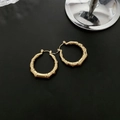 Minimalist gold bamboo hoop earrings with a polished finish on a black background - Titanium Steel Bamboo Ear Buckle / Gold