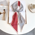 Detail of red and grey geometric silk twilly scarf tied in a bow on a book - Red Grey Beige Patchwork Woven Pattern (LE-256)