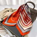 Luxe zijden vierkante sjaal met oranje paardenbitprint over een stijlvolle tas - Oranje