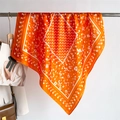 Nahaufnahme eines orangefarbenen Seidenschals mit weißen Blumenmustern und Polka Dots - 70x70cm / Orange