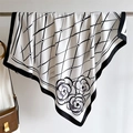 Macro detail of silk texture square scarf featuring black diamond lattice and camellia floral print - White