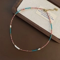 Close-up of handmade beaded necklace with lobster clasp on a rustic wooden tray - Pink Turquoise and Gold Bead Style (01-K27)