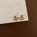 Golden lotus stud earrings with white enamel petals on a textured stone surface - Gold