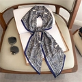 Detailed close-up of blue paisley silk scarf tied in a bow knot on a vintage book - Blue Blue White Paisley Pattern (LE-112)