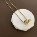 Elegant gold titanium necklace with a zircon safety pin pendant and woven chain links - Gold