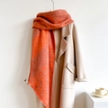 Detailed close-up of bright orange thick wool-like scarf with raw fringe edges - Orange