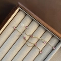 Pendientes largos dorados ondulados con cuatro circonitas rosas en un joyero de madera - Rosa