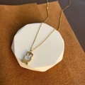 Golden rabbit necklace with shell inlay and bow detail on a white stone pedestal - Gold