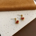 Minimalistische rote Herz-Ohrringe mit Gold-Finish vor einem eleganten Hintergrund - Rotes Herz Tropföl Stil (钛钢#292)