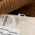 Macro shot of silver triangular earrings with intricate woven texture and hoop clasp - Silver