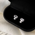 Détail de boucles d'oreilles en perle et zircone dans un écrin à bijoux noir sophistiqué - Argenté