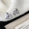 Detail of silver heart stud earrings with cubic zirconia on white knit fabric - Silver