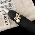 Luxurious gold bow ring with micro-pave zircons and white pearl on a display stand - Golden Bow Pearl Ring