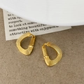 Detailaufnahme goldener Tropfenohrringe mit einer einzigartigen radialen Metallstruktur - Gold