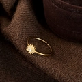Vista macro di anello regolabile a fiore dorato con zirconi su sfondo di velluto marrone - Oro