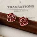 Dettaglio di orecchini a lobo vintage con rose rosse e bordi dorati su un supporto - Smalto a Fiore Rosso Bordeaux