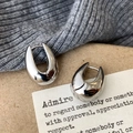 Close-up of minimalist silver horseshoe earrings on gray knit fabric and vintage paper - Silver