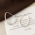 Close-up of silver teardrop earrings with a matte brushed finish on fabric - Small Brushed Style / Silver