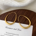 Macro view of matte brushed gold geometric earrings in irregular drop shape on wood and card - Large Brushed Style / Gold