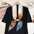 Close-up of a floral silk scarf styled on a black knit top with a coffee lifestyle setup - Autumn Forest Deer (LE-180)