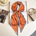 Polka dot silk scarf tied in a bow on a book showing its smooth fabric and pointed ends - Bright Orange Belt Buckle (LE-189)