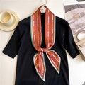 Close-up of narrow polka dot neck scarf tied on a chic black knit top for styling - Brick Red Green Belt Pattern (LE-190)