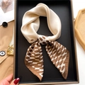 Dettaglio di un elegante foulard a pois beige e marrone annodato su un vassoio - caffè