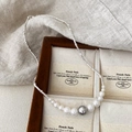 Detailed view of silver twisted chain necklace with gradient pearl accents on velvet - Silver