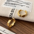 Nahaufnahme goldener Creolen mit Wellentextur und Perlenrand auf rustikalem Hintergrund - Gold